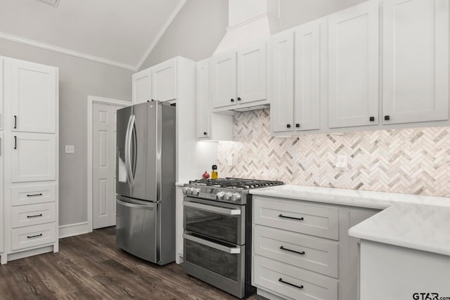 kitchen featuring dark hardwood / wood-style flooring, vaulted ceiling, white cabinets, ornamental molding, and appliances with stainless steel finishes