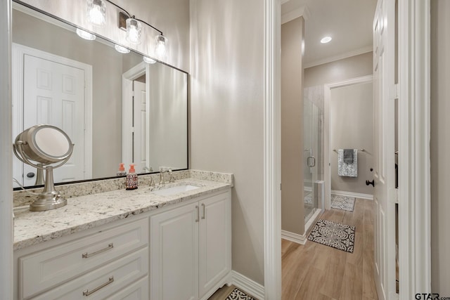 bathroom with vanity, hardwood / wood-style flooring, a shower with door, and ornamental molding