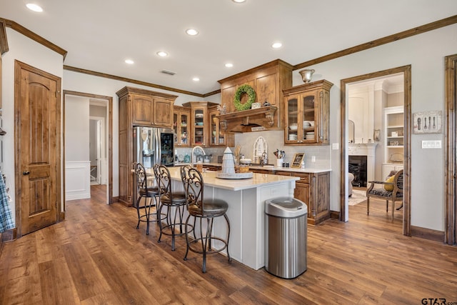 kitchen with decorative backsplash, an island with sink, dark wood-type flooring, and stainless steel refrigerator with ice dispenser