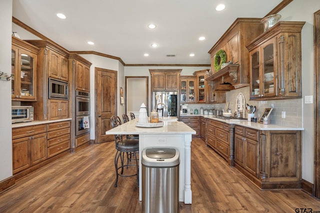 kitchen featuring a center island with sink, dark hardwood / wood-style floors, appliances with stainless steel finishes, and a breakfast bar