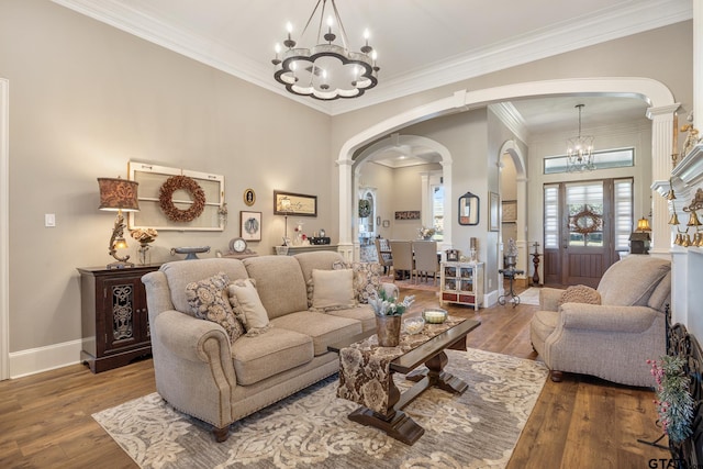 living room featuring hardwood / wood-style flooring, decorative columns, ornamental molding, and a notable chandelier