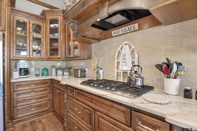 kitchen featuring stainless steel gas stovetop, dark hardwood / wood-style flooring, light stone countertops, and backsplash