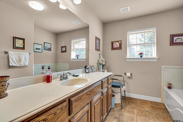 bathroom with vanity, a healthy amount of sunlight, toilet, and a bathtub