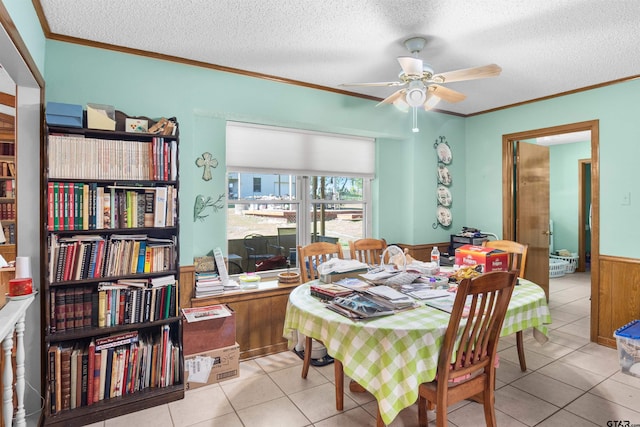 tiled dining area featuring ornamental molding, wooden walls, a textured ceiling, and ceiling fan