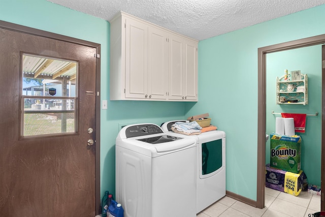 clothes washing area featuring washer and clothes dryer, cabinets, a textured ceiling, and light tile patterned flooring