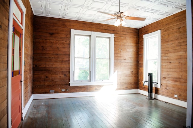 spare room featuring dark hardwood / wood-style flooring, a wealth of natural light, and wooden walls