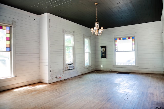 spare room with wood-type flooring, a healthy amount of sunlight, and a notable chandelier