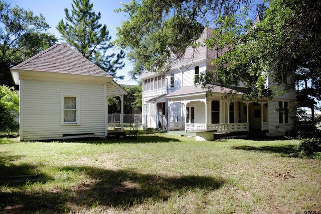 back of house featuring a porch and a lawn