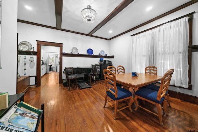 dining area featuring wood-type flooring, a chandelier, beamed ceiling, and ornamental molding