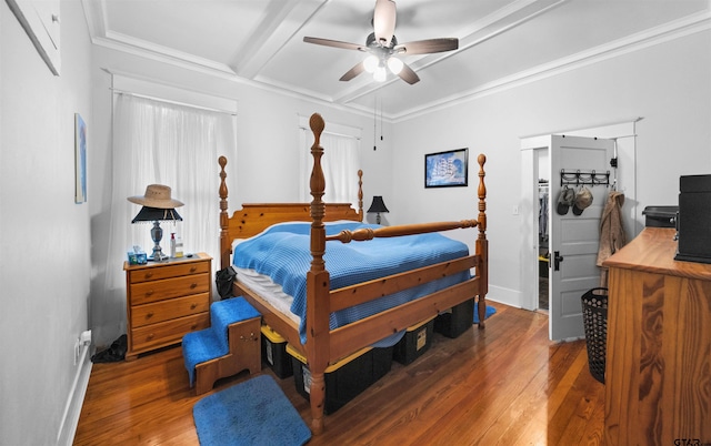 bedroom with ceiling fan, dark wood-type flooring, ornamental molding, and beamed ceiling