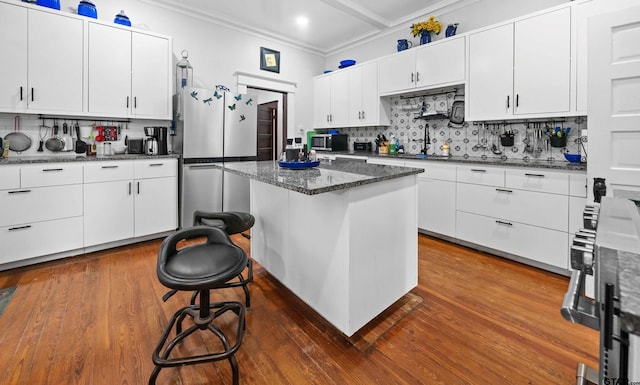 kitchen with white cabinets, a center island, appliances with stainless steel finishes, decorative backsplash, and a breakfast bar area