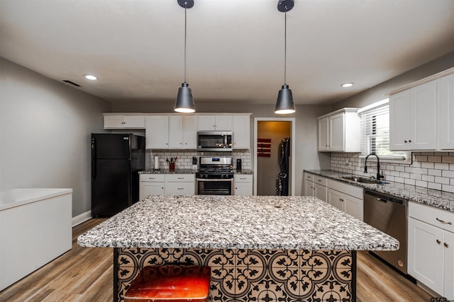 kitchen featuring light hardwood / wood-style floors, stainless steel appliances, a center island, sink, and white cabinetry