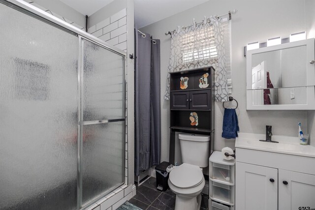 bathroom with tile patterned flooring, vanity, toilet, and a shower with shower door