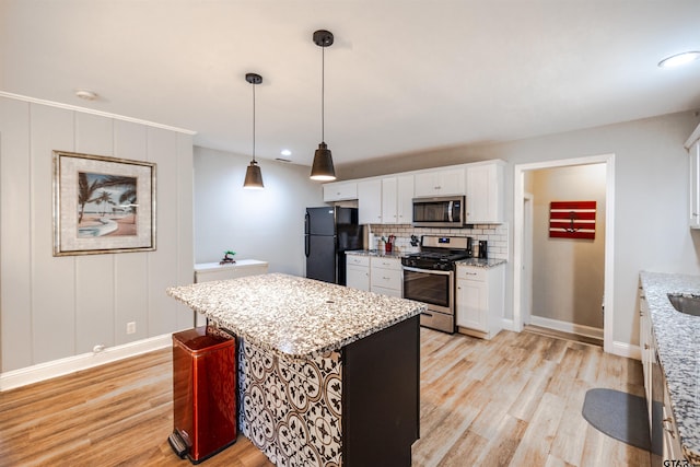 kitchen featuring a kitchen island, white cabinetry, appliances with stainless steel finishes, hanging light fixtures, and light hardwood / wood-style floors