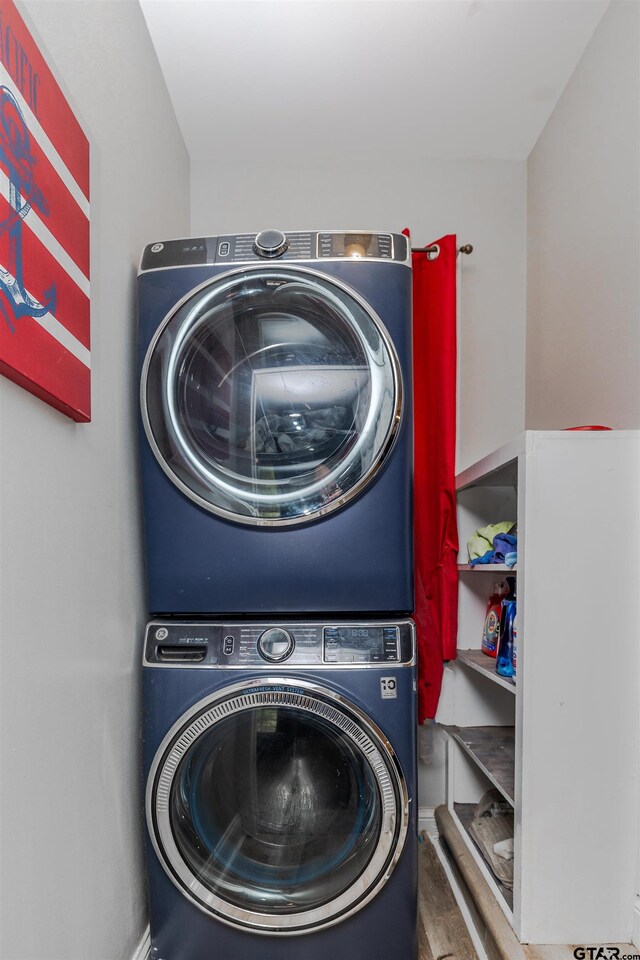 laundry room with stacked washer / dryer and hardwood / wood-style flooring