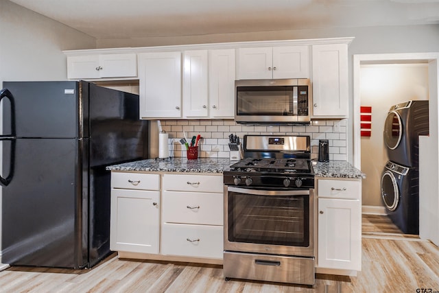 kitchen featuring stacked washer / dryer, light hardwood / wood-style flooring, white cabinets, and stainless steel appliances