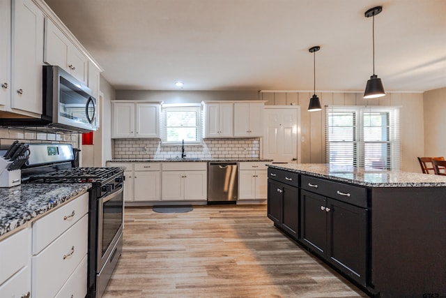 kitchen featuring a kitchen island, pendant lighting, appliances with stainless steel finishes, and plenty of natural light