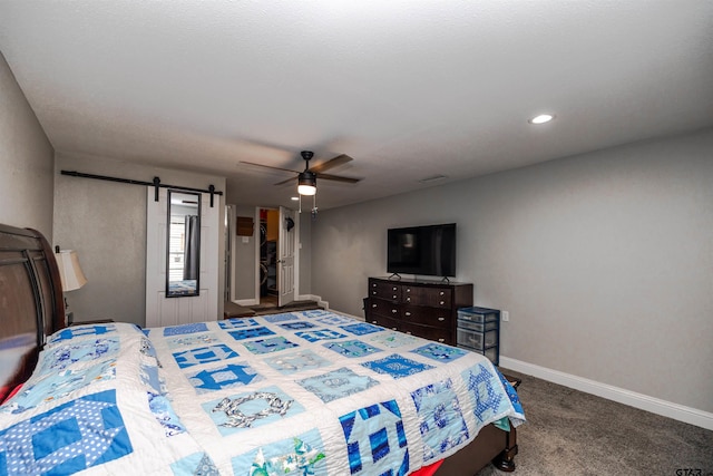 carpeted bedroom with a barn door and ceiling fan