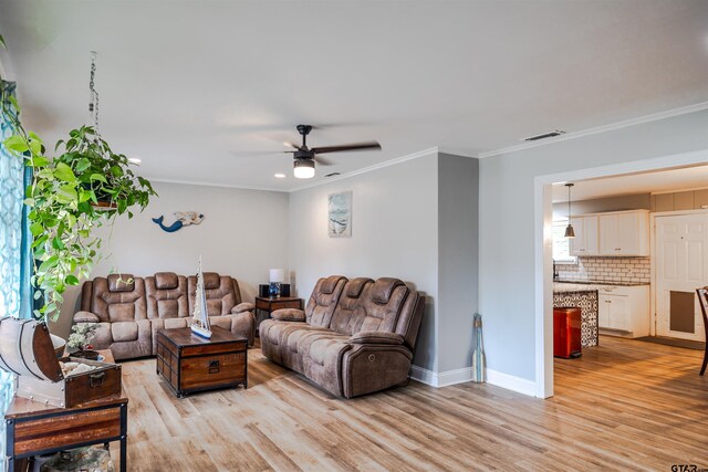 living room featuring crown molding, a healthy amount of sunlight, ceiling fan, and light hardwood / wood-style flooring