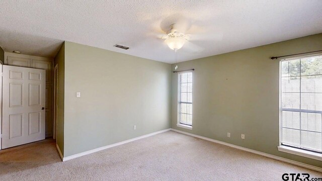 415 Amberwood Cir, Tyler, TX 75701 - empty room with light colored carpet, baseboards, a textured ceiling, and a ceiling fan