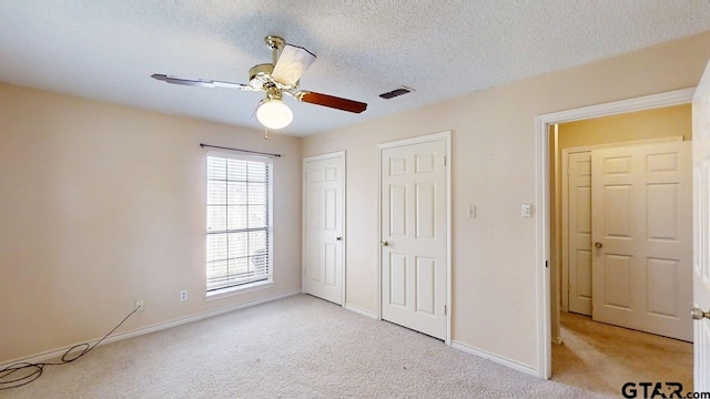415 Amberwood Cir, Tyler, TX 75701 - unfurnished bedroom with light colored carpet, multiple closets, baseboards, a textured ceiling, and ceiling fan