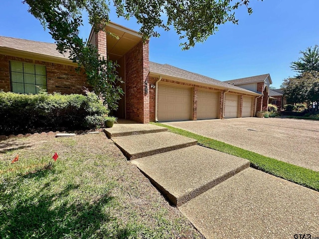 415 Amberwood Cir, Tyler, TX 75701 - view of front facade featuring an attached garage, brick siding, concrete driveway, and a chimney