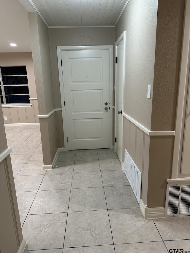 doorway featuring wood ceiling, ornamental molding, and light tile patterned flooring