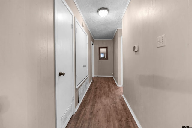 corridor featuring wood-type flooring, a textured ceiling, and ornamental molding