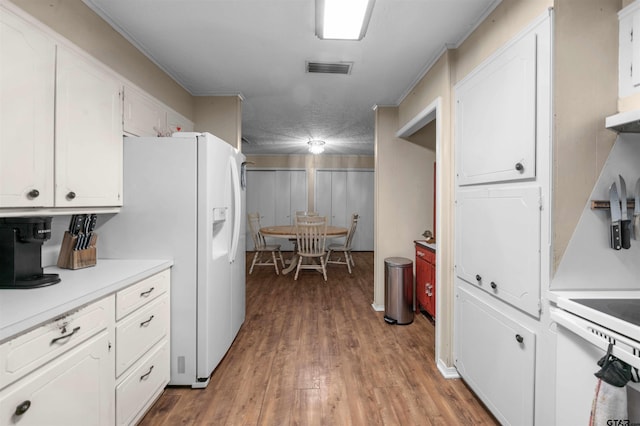 kitchen with a textured ceiling, light hardwood / wood-style floors, white cabinetry, and white fridge with ice dispenser