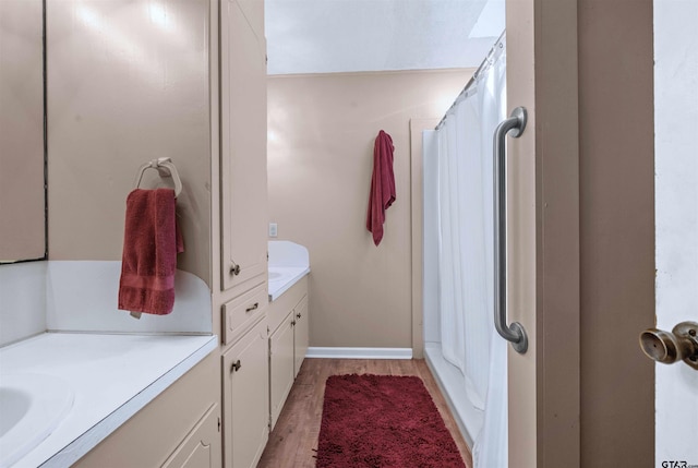 bathroom with hardwood / wood-style flooring, vanity, and walk in shower