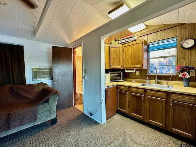 kitchen with vaulted ceiling with beams, wood walls, sink, and light carpet