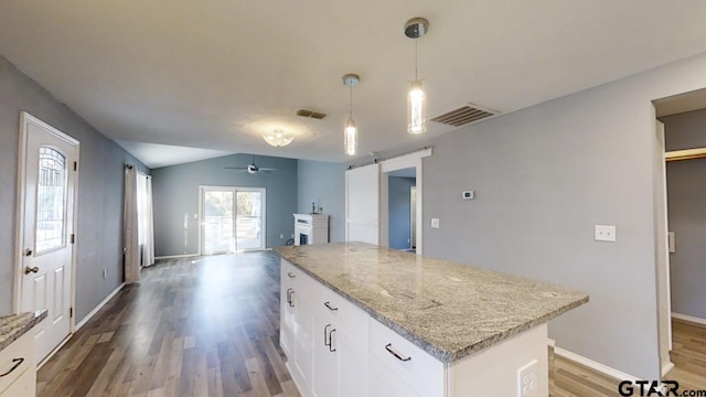 kitchen with a barn door, white cabinets, decorative light fixtures, and hardwood / wood-style flooring