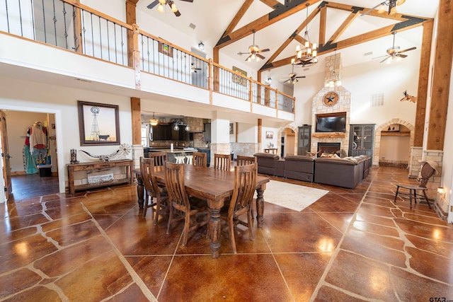 dining space with beamed ceiling, ceiling fan, a fireplace, and high vaulted ceiling