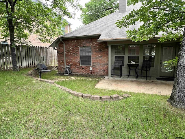 5609 Andover Dr, Tyler, TX 75707 - back of house featuring fence, brick siding, a chimney, a lawn, and a patio