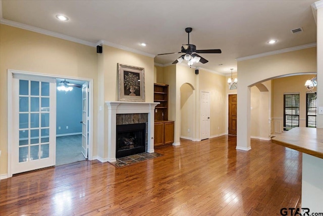 5609 Andover Dr, Tyler, TX 75707 - unfurnished living room featuring arched walkways, ceiling fan with notable chandelier, wood finished floors, and a fireplace