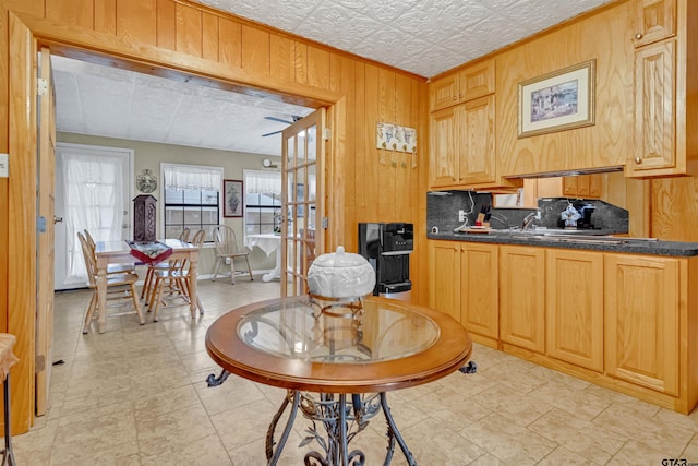 kitchen featuring wood walls, light brown cabinets, a textured ceiling, light tile patterned floors, and decorative backsplash