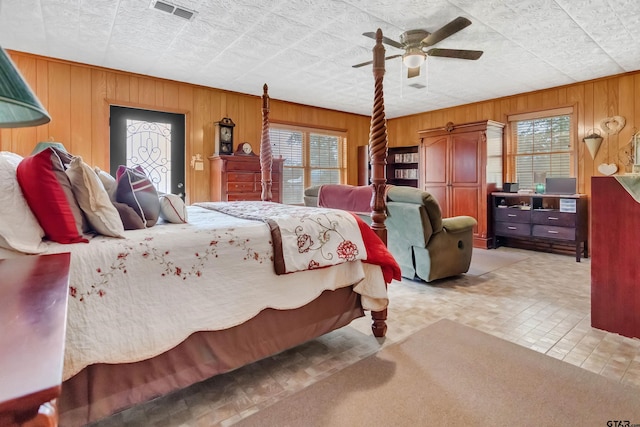 bedroom featuring multiple windows, wooden walls, and ceiling fan