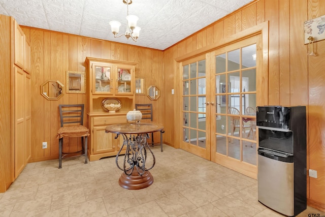 interior space featuring french doors, wood walls, and an inviting chandelier