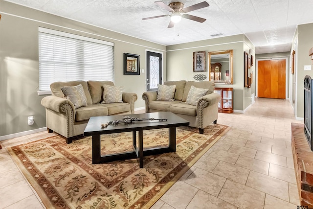 living room featuring ceiling fan, a textured ceiling, and tile patterned flooring