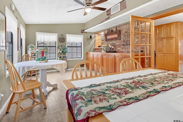 dining space featuring a textured ceiling, lofted ceiling, light tile patterned floors, and ceiling fan