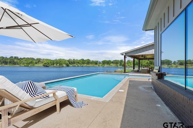 pool featuring a patio area, a ceiling fan, and a water view