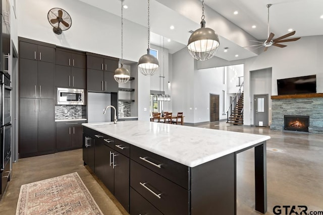 kitchen featuring recessed lighting, a sink, stainless steel microwave, finished concrete flooring, and high vaulted ceiling