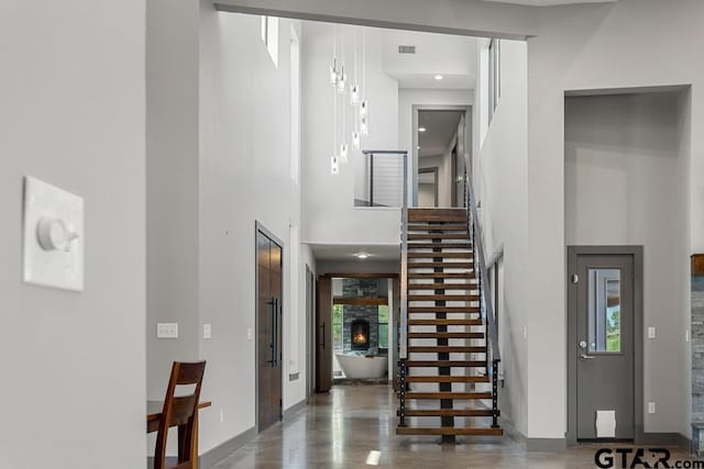 foyer with a fireplace, a towering ceiling, stairs, and baseboards