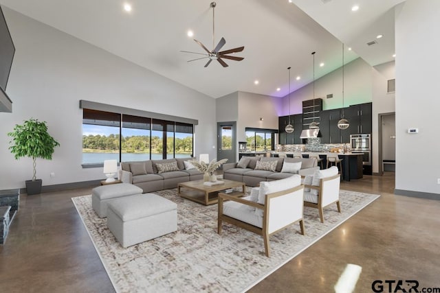 living area featuring baseboards, a ceiling fan, high vaulted ceiling, and finished concrete floors