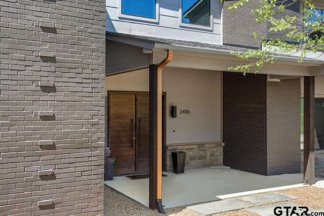 view of exterior entry featuring brick siding