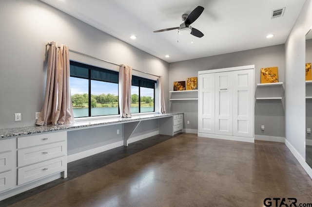 interior space featuring baseboards, concrete flooring, visible vents, and built in desk