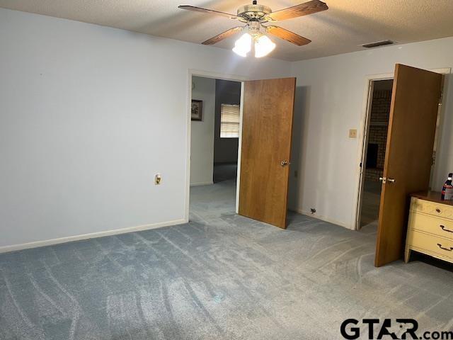 unfurnished bedroom featuring visible vents, a ceiling fan, a textured ceiling, carpet, and baseboards