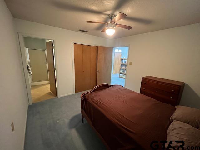 bedroom with a closet, visible vents, ceiling fan, and carpet