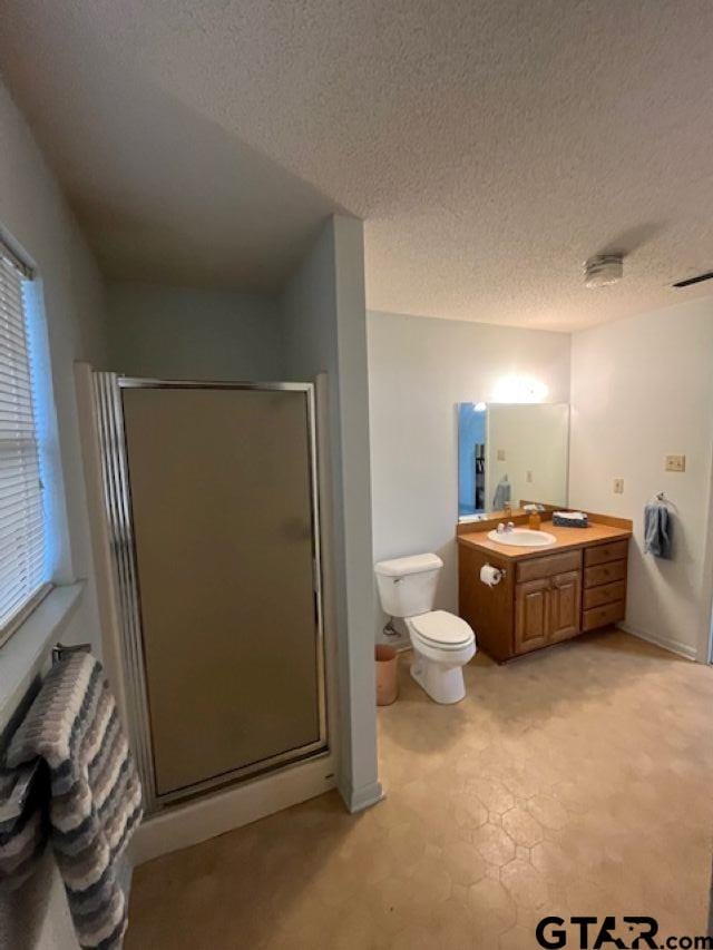 full bathroom with toilet, a stall shower, vanity, and a textured ceiling