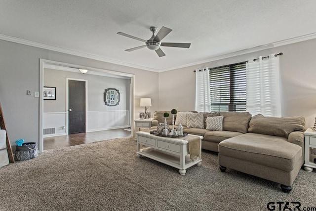 carpeted living room with a ceiling fan, visible vents, crown molding, and a textured ceiling